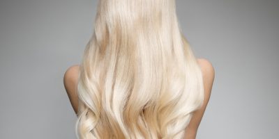 Portrait Of Beautiful Young Blond Woman With Long Wavy Hair. Back view